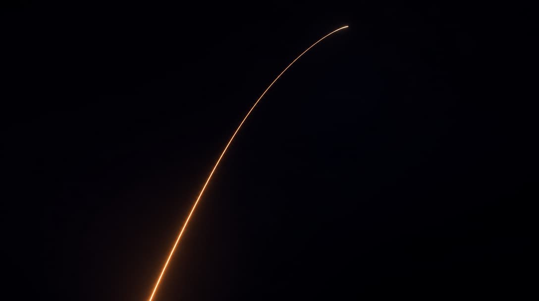 A single warm light trail arcing upward through darkness